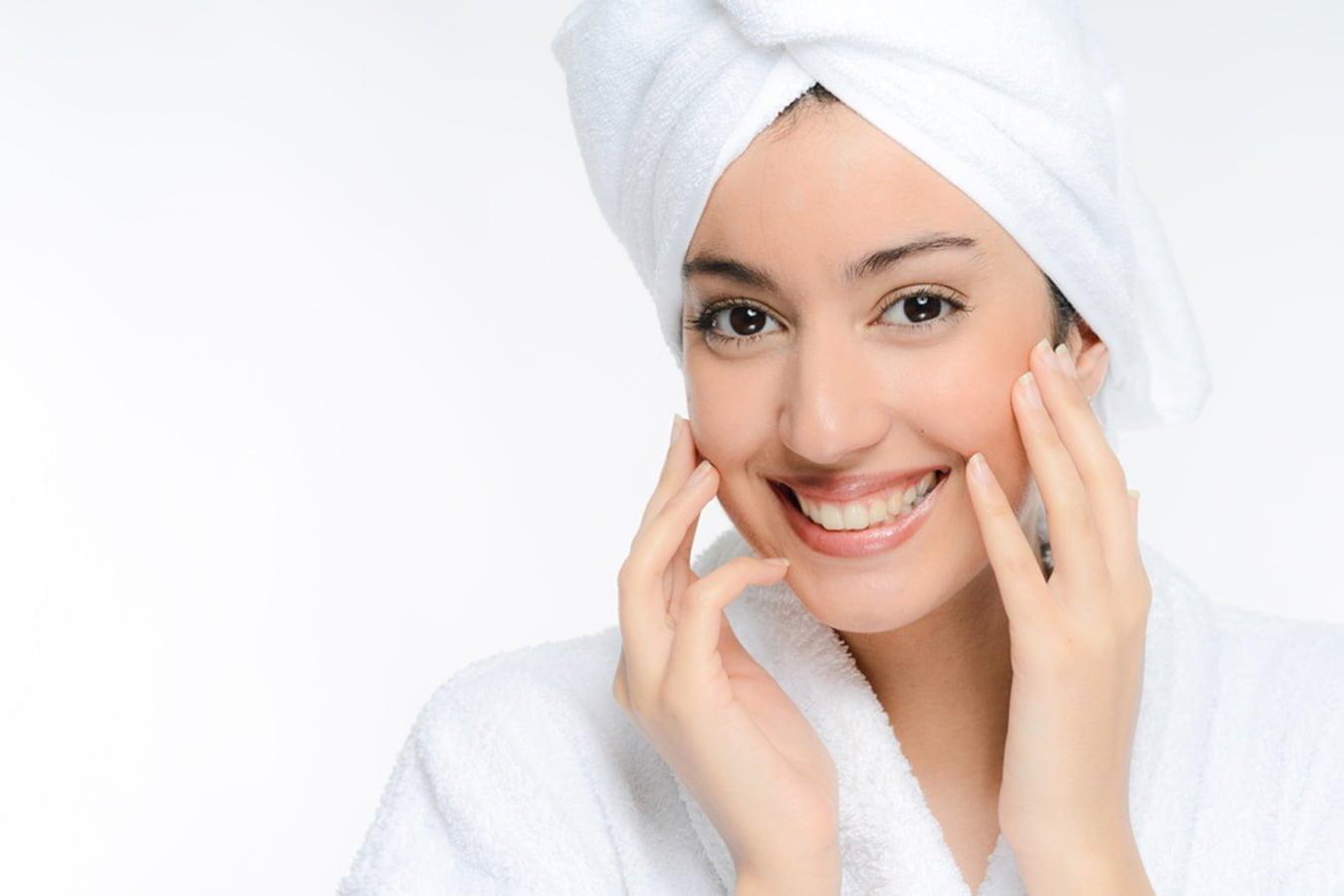 Smiling woman with clear skin in white towel and bathrobe, natural skincare concept