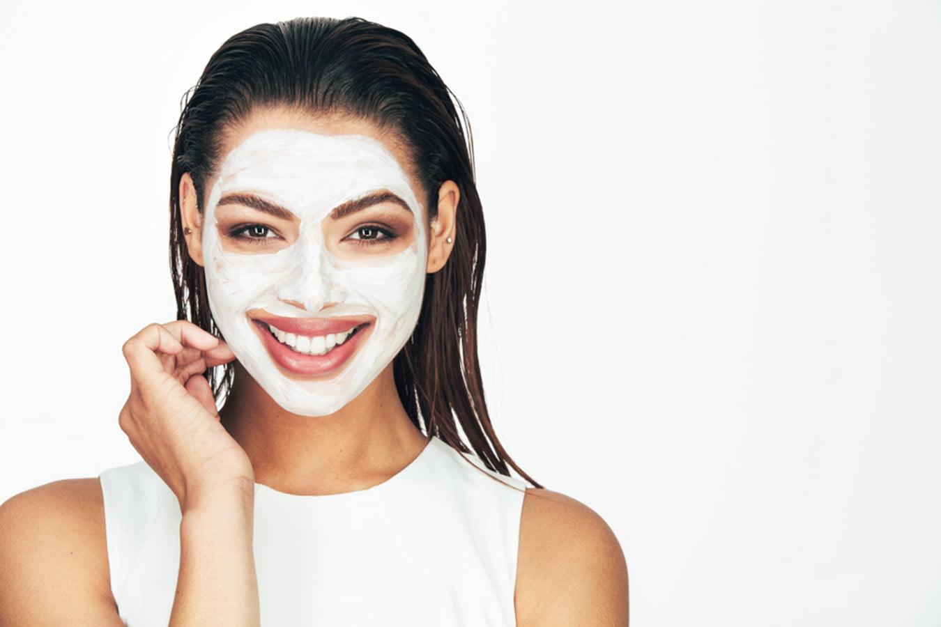 Smiling woman with white face mask, wet hair, skincare beauty treatment