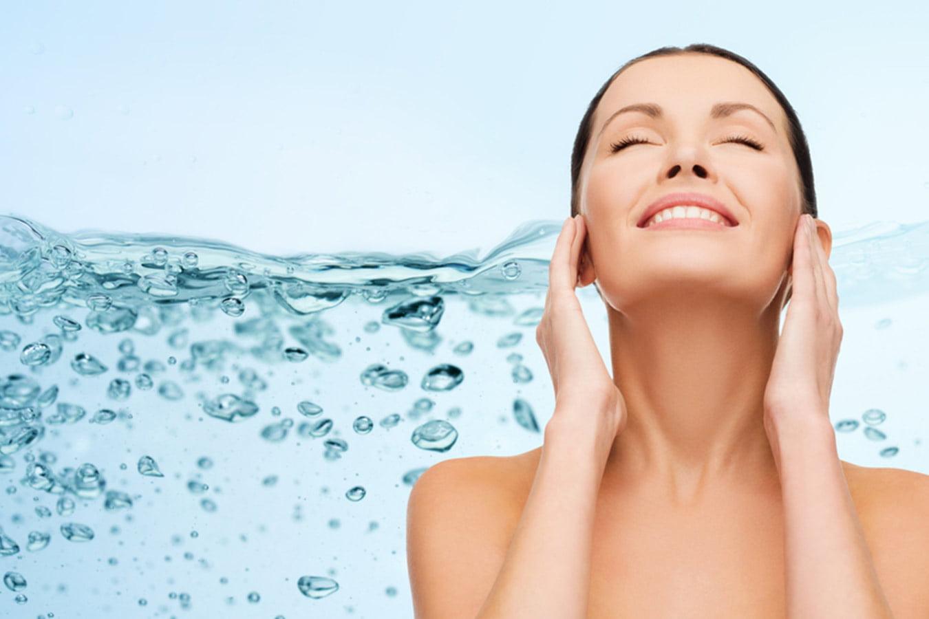 Smiling woman cleansing face with water, clear skin, natural skincare concept