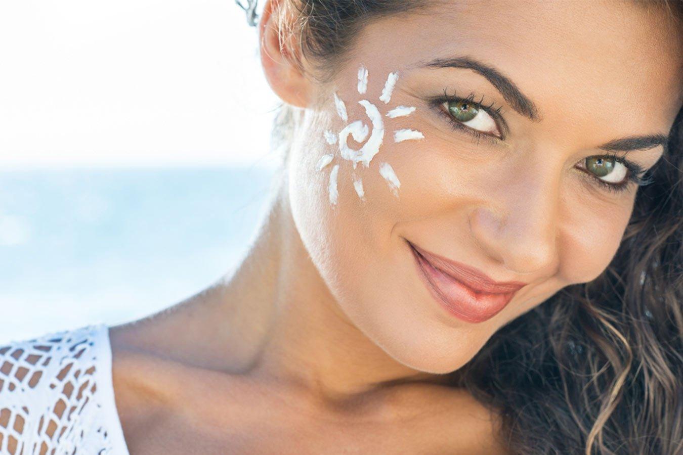 Woman at beach with sunscreen sun design on cheek, promoting natural skincare and sun protection