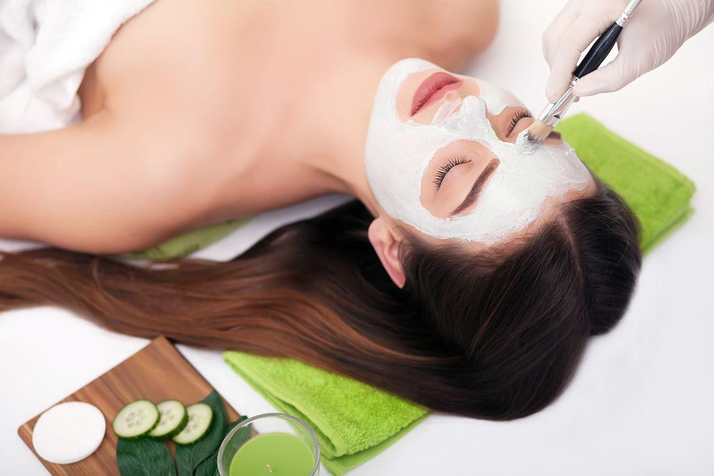 Woman receiving rice flour face mask spa treatment, skincare ingredients visible nearby