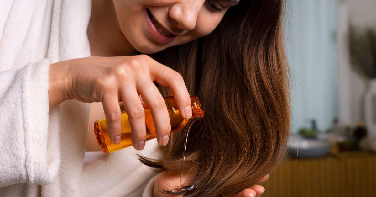 Woman applying mustard oil to long brown hair for natural hair care