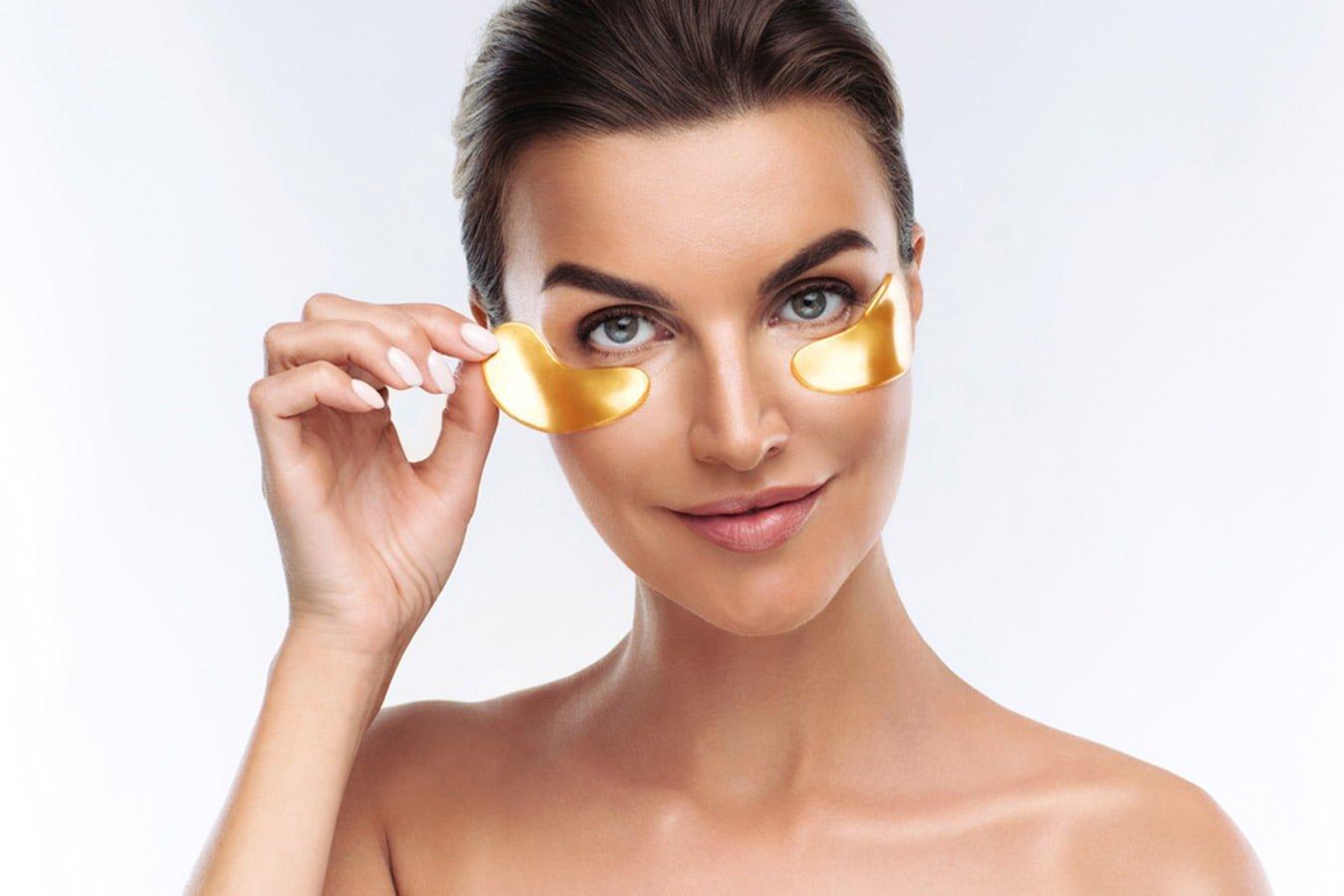 Woman applying gold under eye patches for skincare and dark circle treatment