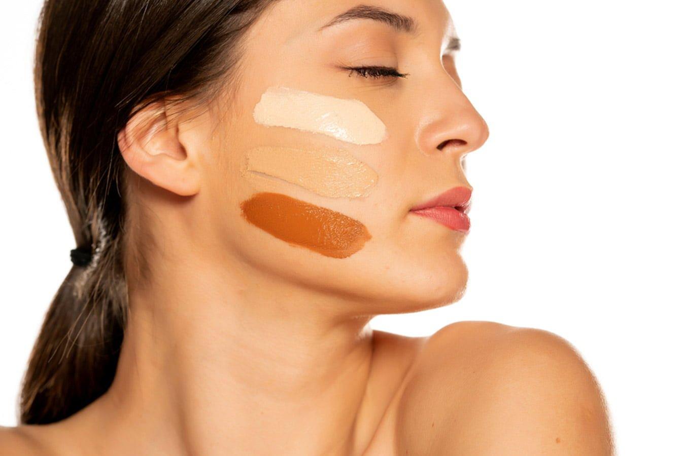 Woman with foundation swatches in varying skin tones on cheek, skincare and beauty concept