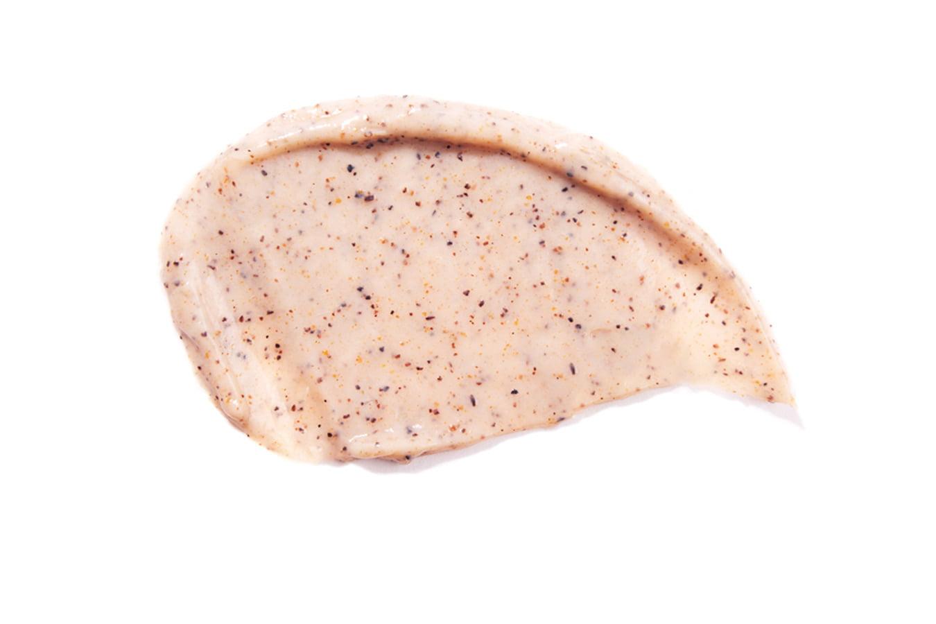 Close-up of creamy herbal face scrub with exfoliating natural particles on white background