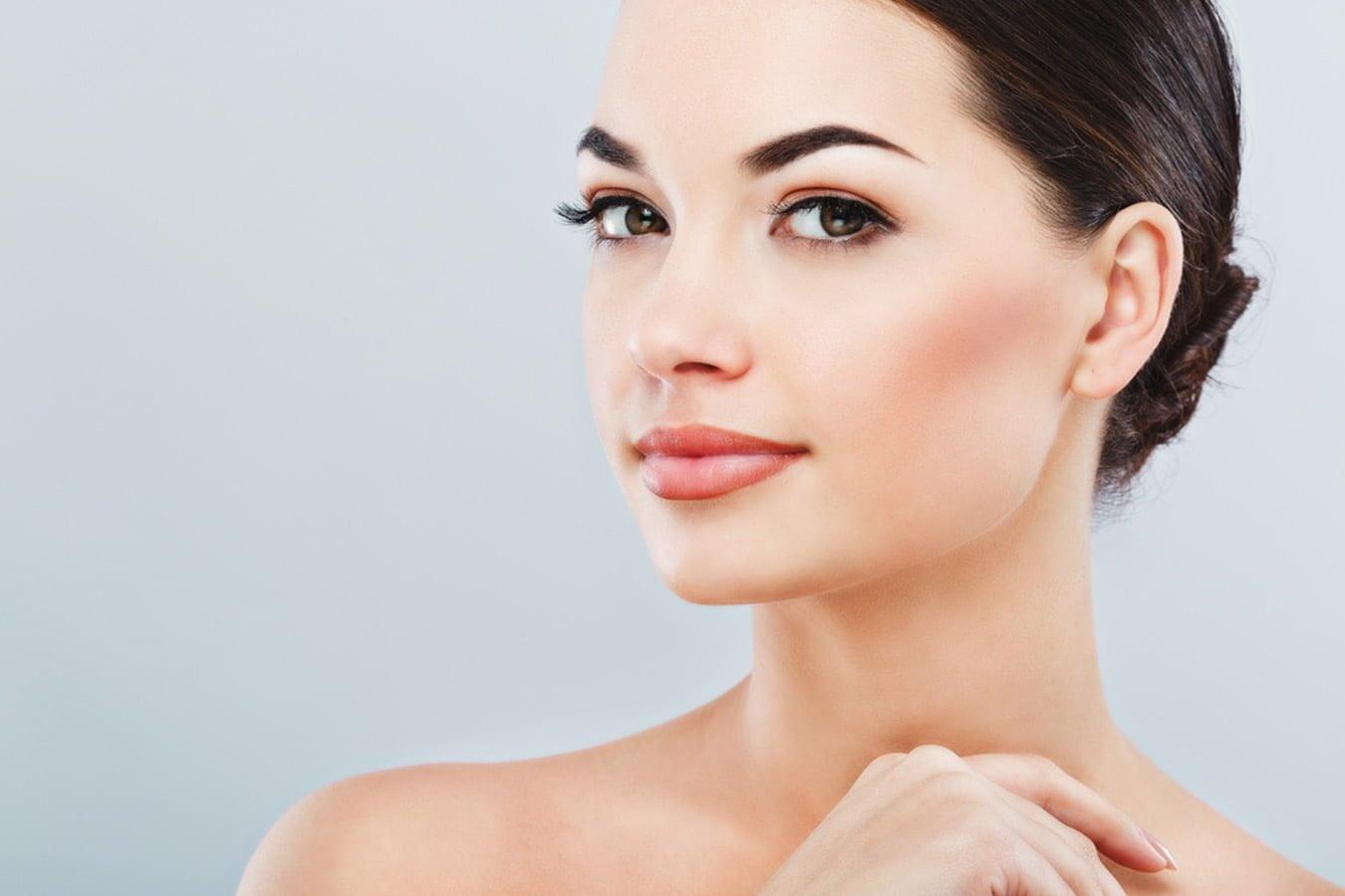 Woman with glowing, clear skin and smooth complexion on a light background
