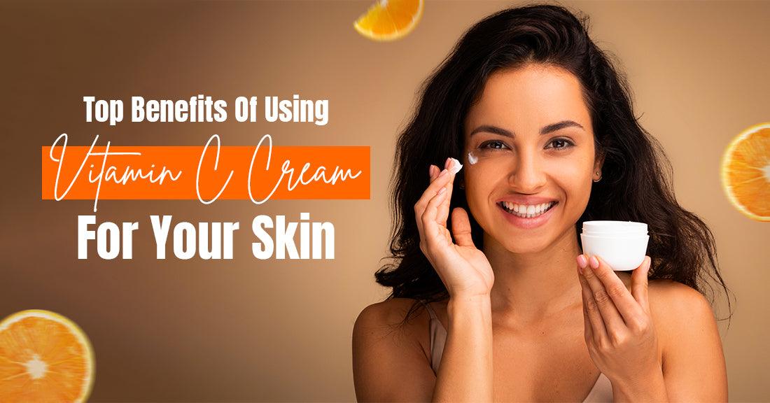 Smiling woman applying Vitamin C cream with the text "Top Benefits Of Using Vitamin C Cream For Your Skin" on a beige background with orange slices