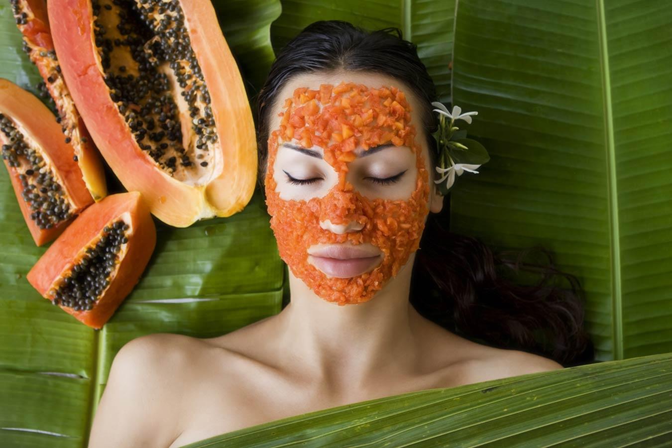 Woman with papaya face mask relaxing on banana leaves, sliced papaya nearby, natural skincare