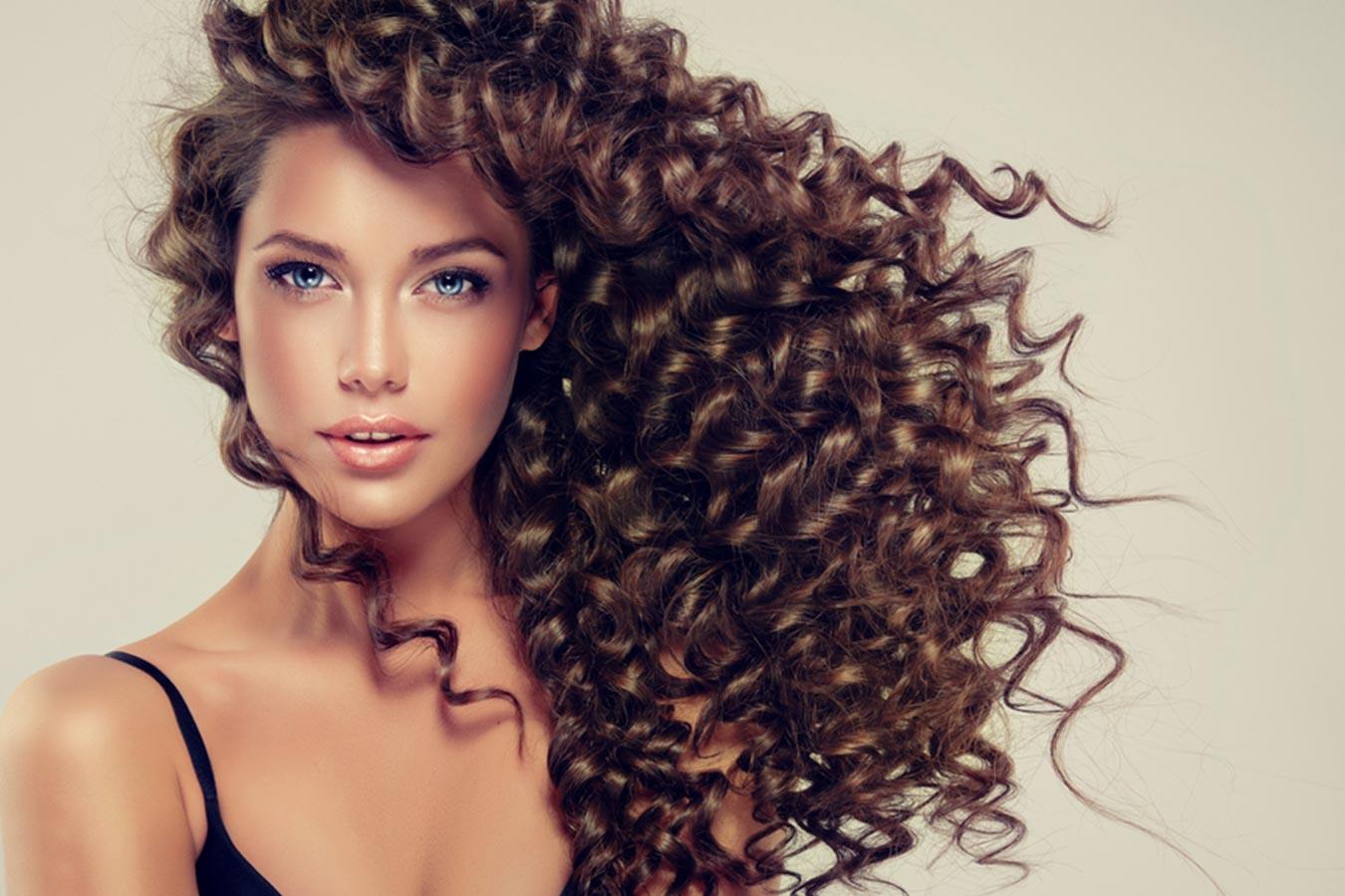 Woman with defined, voluminous, shiny curly hair and glowing skin